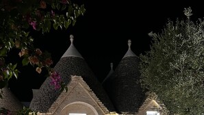 A stone house with a central door, multiple gabled roofs, and a well-lit exterior. - Villa 'Dimora Dormio' with Private Pool, Wi-Fi, and Air Conditioning (monopoli)