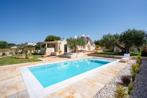 A swimming pool with a tiled deck, a pergola, and a small building with a conical roof. - Villa 'Dimora Dormio' with Private Pool, Wi-Fi, and Air Conditioning (monopoli)