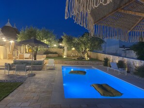 A swimming pool with lounge chairs, a covered seating area, and a stone wall. - Villa 'Dimora Dormio' with Private Pool, Wi-Fi, and Air Conditioning (monopoli)