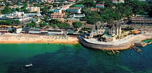 Una vista aerea di una località costiera con una spiaggia, un molo e degli edifici.