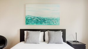 A neatly made bed with a white duvet and two grey pillows, a black headboard, and a small bedside table with a lamp. - The Light Stay at Cascais (Cascais)