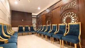 A row of blue upholstered chairs with gold accents, arranged in a formal setting with wooden paneling and decorative cutouts on the walls. - Retaj Inn Hotel (Makkah)