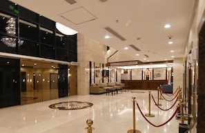 Um hall amplo com balcão de recepção, área de estar e padrão decorativo no chão.