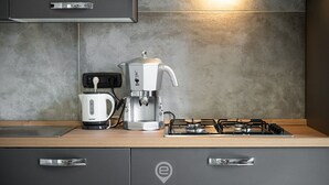 Une cuisine moderne équipée d’une machine à café, d’une bouilloire et d’une cuisinière à gaz.