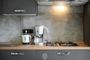 Una cocina moderna con cafetera, hervidor y estufa a gas.
