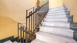 Un escalier avec des marches en marbre et des rampes en métal noir.