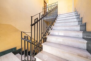 Una escalera con escalones de mármol y barandillas de metal negro.