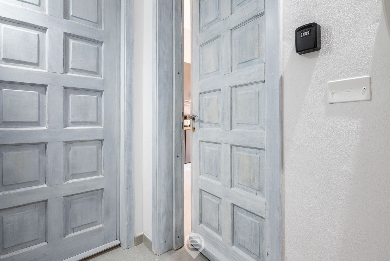 Un juego de puertas dobles con acabado gris claro, un portero automático y un interruptor de luz.