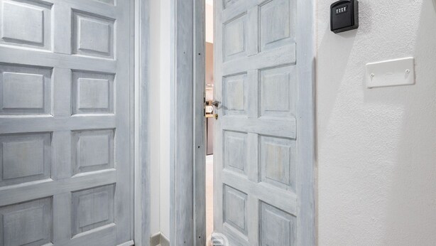 A set of double doors with a light gray finish, a wall-mounted intercom, and a light switch. - Cagliari Shopping District Flat (Cagliari)