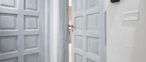 Un juego de puertas dobles con acabado gris claro, un portero automático y un interruptor de luz.