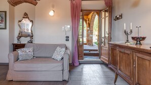 Una stanza con un divano, uno specchio, un armadietto in legno e una porta che dà sull'esterno.