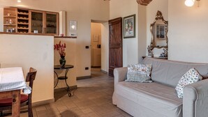 Un accogliente soggiorno con un divano, un tavolo da pranzo con sedie, un mobile contenitore in legno con vetrate e uno specchio a parete.