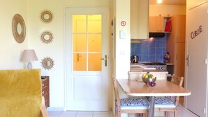 A compact kitchen with a dining area, a white door with glass panels, and a kitchenette with a stove and cabinets. - Cosy flat close to the centre of Auray (Auray)