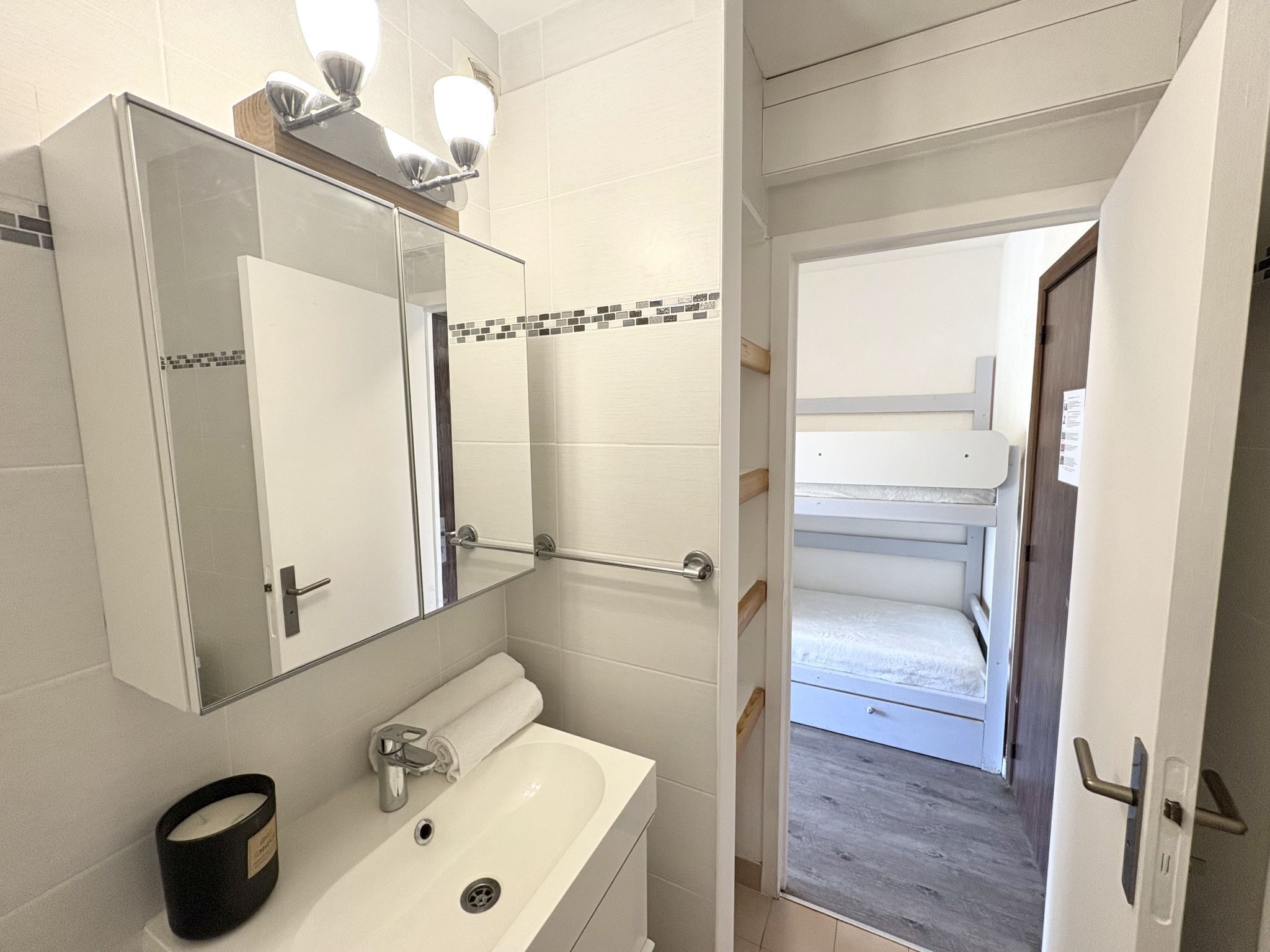 A bathroom with a white sink, a mirror, and a towel rack.