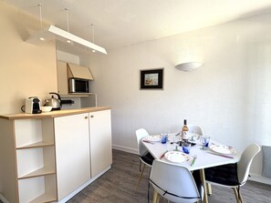 Eine kleine Küche mit Mikrowelle, Wasserkocher und Toaster, ein Esstisch für vier Personen und ein gerahmtes Bild an der Wand.