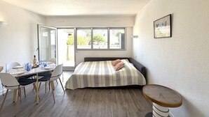 A bedroom with a bed, a bedside table, a chair, a table with glasses, and a window. - Jetée des Marins by Interhome (Arcachon)