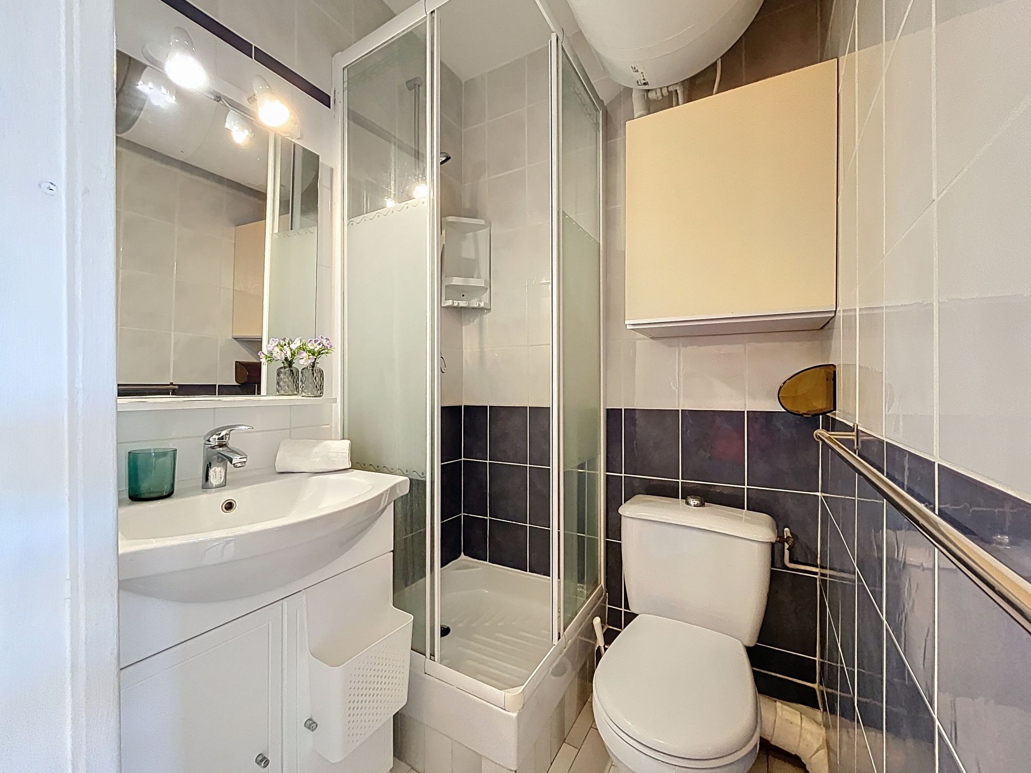 A modern bathroom with a white sink, mirror, and toilet.
