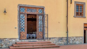 A building with a stone foundation, a wooden door with metal bars, and a brick-paved entrance.