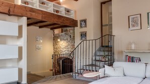 A cozy room with a fireplace, a staircase, and a white sofa.