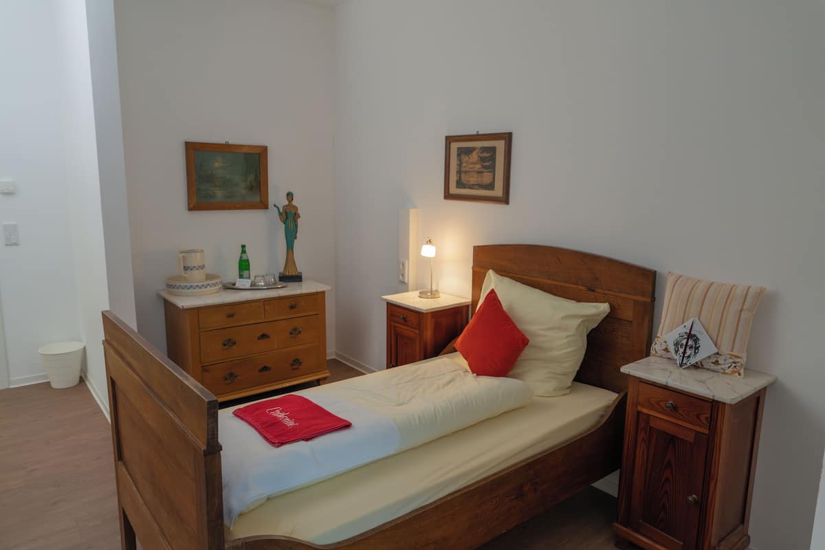 A neatly arranged bedroom with a wooden bed, a nightstand, a dresser, and a small cabinet.