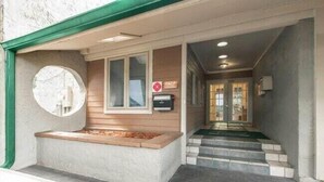 A building entrance with a wooden bench, a mailbox, and a staircase leading to the entrance.