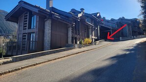 A large, multi-story building with a stone facade and a steeply pitched roof. - Modern duplex near slopes with parking (Courchevel 1550)