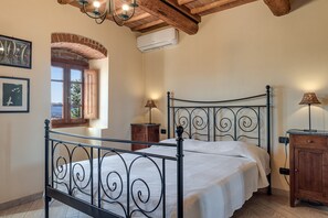 Une chambre à coucher avec un lit en métal, une armoire en bois, une table de chevet et une fenêtre donnant sur un beau paysage.