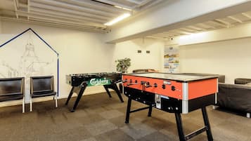Una habitación con dos mesas de fútbol de mesa, un mural en la pared y un espacio de estar.