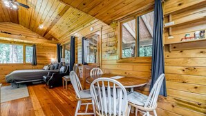 Un interior de cabaña acogedor con cama, zona de estar y mesa de comedor.