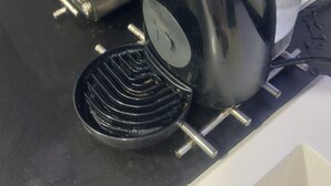 Une machine à café dotée d’un réservoir d’eau transparent et d’un bac de récupération noir.