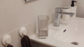 Une salle de bain avec un miroir, un lavabo, un verre et un porte-serviettes.