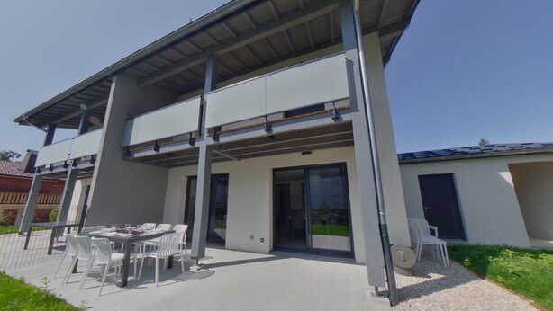 A modern two-story house with a covered patio area.