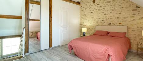 Un dormitorio con una cama grande, una puerta corredera y un muro con estampado de piedra.