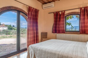 Un dormitorio con un ventanal grande, una cama y una silla.