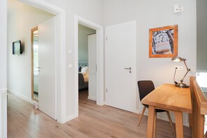 A room with a wooden dining table, a single chair, a wall-mounted lamp, and a door leading to another room. - Welcome to Störtebekers Reethus - your exclusive vacation home on Usedom (Loddin)
