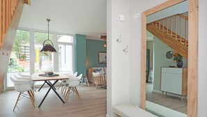 A dining area with a wooden table and chairs, a hanging light fixture, and a large mirror reflecting a staircase. - Welcome to Störtebekers Reethus - your exclusive vacation home on Usedom (Loddin)