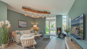 A modern living room with a sofa, a coffee table, a fireplace, and a television. - Welcome to Störtebekers Reethus - your exclusive vacation home on Usedom (Loddin)