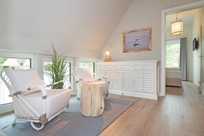 Een kamer met een witte stoel, een houten tafel en een kast met shutters.