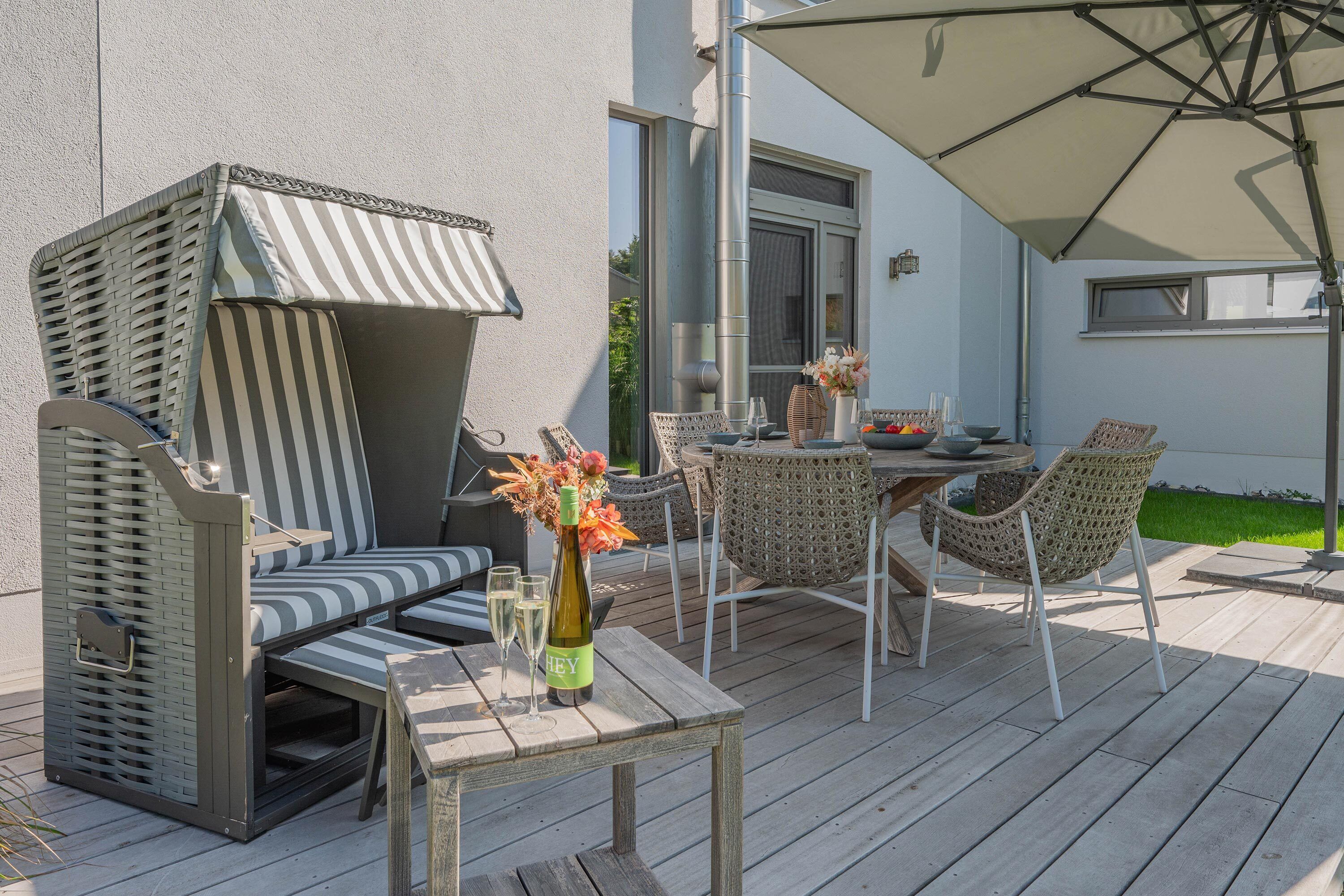 An outdoor patio with a table, chairs, a cushioned seating area, and a large umbrella.