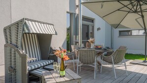 An outdoor patio with a table, chairs, a cushioned seating area, and a large umbrella. - Welcome to Störtebekers Reethus - your exclusive vacation home on Usedom (Loddin)