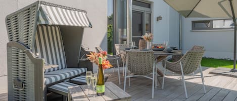 An outdoor patio with a table, chairs, a cushioned seating area, and a large umbrella.