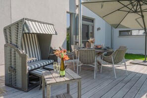 An outdoor patio with a table, chairs, a cushioned seating area, and a large umbrella.
