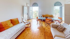 A spacious living area with a sofa, a dining table, and a balcony with arched windows. - Spacious 3P in quiet palace, sea view in Menton (Menton)