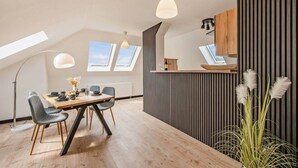 A modern kitchen with a wooden countertop, a dining area with a table and chairs, and a large window. - Family-friendly vacation apartment close to the beach with parking & local shuttle (Ostseebad Kölpinsee)