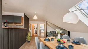 A modern dining area with a wooden table, blue plates, and grey chairs. - Family-friendly vacation apartment close to the beach with parking & local shuttle (Ostseebad Kölpinsee)