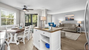 A spacious living area with a dining table, white cabinets, and a sofa. - Ocean Greens Unit E201 (North Myrtle Beach)