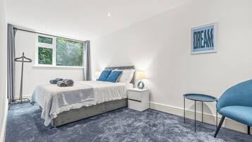 A bedroom with a bed, bedside tables, a chair, and a window.
