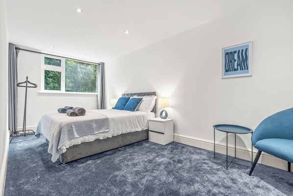 A bedroom with a bed, bedside tables, a chair, and a window.