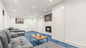 A modern living room with grey sofas, a wooden coffee table, and a fireplace.