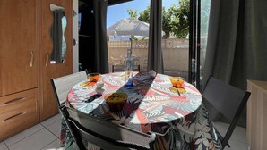 A dining area with a round table, chairs, a cabinet, and a view of the outdoors. - Pavilion with Sunny Terrace, Parking - Gruissan (Gruissan)